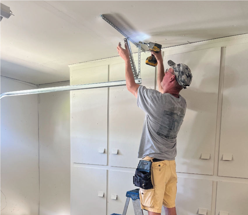 Technician in a brown and orange uniform performing a garage door repair in Dinuba, CA