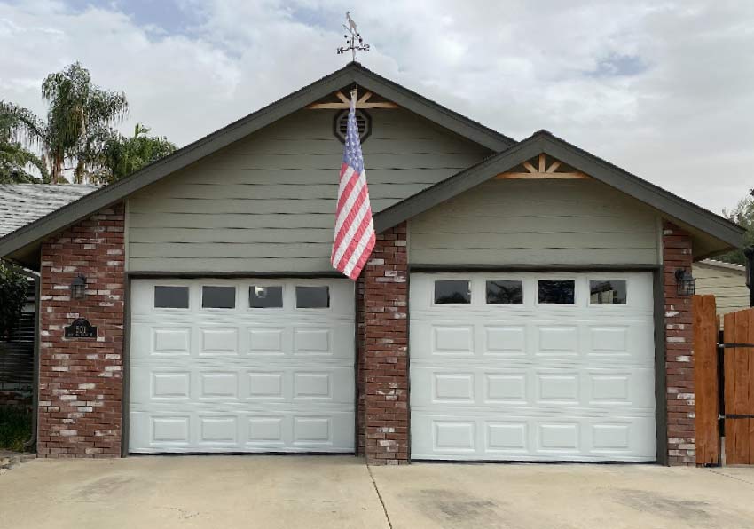 White raised-panel garage doors installed by Browns Garage Door on a home featuring an American flag.
