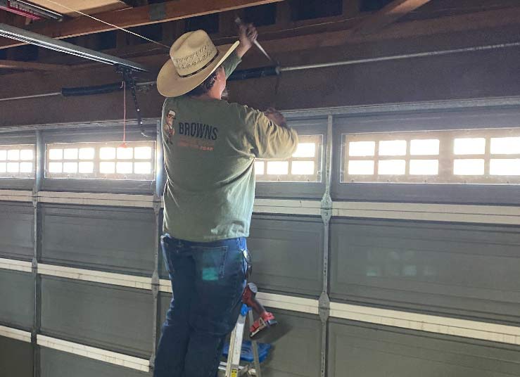 Expert technician adjusting high-tension springs during a garage door service call in the Central Valley.