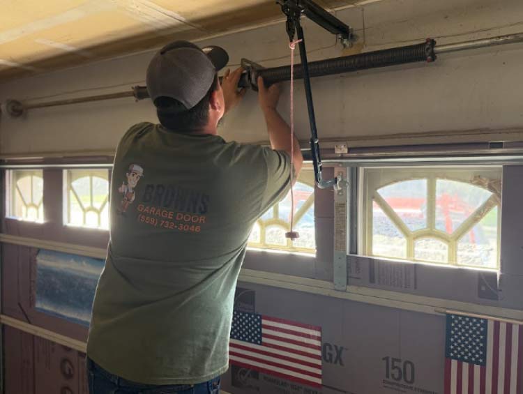 A Browns Garage Door technician performing a professional garage door spring repair on a residential torsion system.